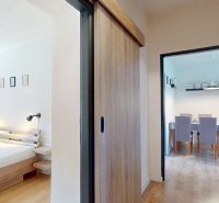Schlafzimmer mit Bett, Schiebetüren, Zugang zum Esszimmer und Holzboden.
