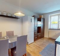 Küche in einer 2-Zimmer-Wohnung mit hellen Wänden und Geräten, Boden mit Holzdekor.