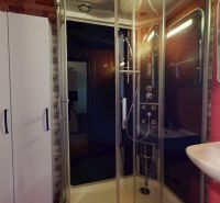 Duschkabine mit Glastüren und weißem Waschbecken in einer 2-Zimmer-Wohnung.