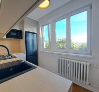 Küche in einer 2-Zimmer-Wohnung mit Holzboden und großen Fenstern.