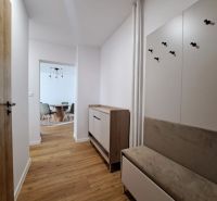 Der Flur in einer 2-Zimmer-Wohnung mit einem Boden in Holzoptik, einem Flurmöbel und einem Essbereich.