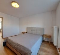 Schlafzimmer mit Bett und Nachttischen, Boden mit Holzdekor in einer 2-Zimmer-Wohnung.