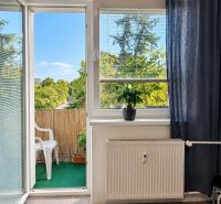 Wohnzimmer in einer 3-Zimmer-Wohnung mit Blick auf den Balkon und Grünflächen.