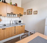 Küche in einer 3-Zimmer-Wohnung mit Holzboden, weißen Wänden und Holzschränken.