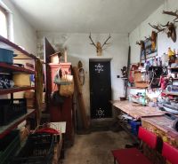 Ein Stauraum mit Regalen und Tischen in einem Einfamilienhaus, dekoriert mit Geweihen an der Wand.