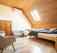 Dachzimmer mit Bett, Sessel, Dachfenster und Holzboden.