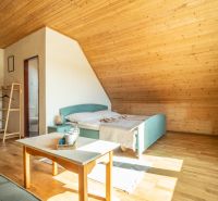 Dachzimmer mit Bett, Tisch und Boden mit Holzdekor im Hotel.
