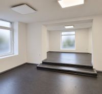 Ein helles Büro mit einem dunklen Boden in Holzoptik und einer Treppe im Raum.