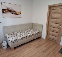 Ein Zimmer in einer 3-Zimmer-Wohnung mit einem Boden in Holzoptik, einem Sofa und einem Bürostuhl.