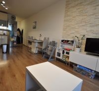Wohnzimmer mit Holzboden, Küche, Esstisch und TV-Schrank.