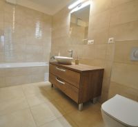 Badezimmer in einer 3-Zimmer-Wohnung mit Badewanne, Waschbecken und Schrank mit Holzdekor.
