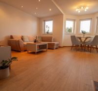 Wohnzimmer in einem Einfamilienhaus mit Holzboden und bequemen Sitzgelegenheiten.