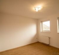 Ein Zimmer in einem Einfamilienhaus mit einem Holzboden und zwei Fenstern.