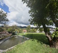 Ein Garten mit einem Teich und Bäumen auf einem Grundstück in Oščadnica in der Straße Košariská.