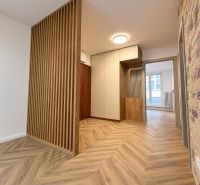 Innenraum einer 3-Zimmer-Wohnung mit gemauerter Wand und Boden in Holzoptik.