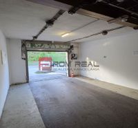 Der Innenraum einer Garage mit offenen Türen, weißen Wänden und einer Ausfahrt nach draußen.