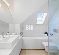 Badezimmer in einer 2-Zimmer-Wohnung mit Badewanne und Dachfenstern, Boden mit Holzdekor.