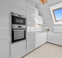 Moderne Küche in einer 2-Zimmer-Wohnung mit weißen Schränken und Dachfenster.