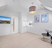 Wohnzimmer mit Holzboden, Fernseher und blauem Stuhl in einer Zweizimmerwohnung.