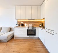 Küche in einer 2-Zimmer-Wohnung mit Holzboden und weißen Schränken.