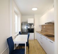 Küche mit weißen Schränken und Holzboden in einer Zweizimmerwohnung.