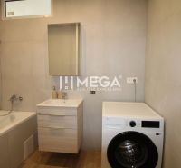 Badezimmer in einer 2-Zimmer-Wohnung mit Badewanne, Waschmaschine und Boden mit Holzdekor.