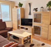 Wohnzimmer mit braunem Sofa, Holzmöbeln und Boden mit Holzdekor.