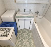 Badezimmer mit Waschbecken, Badewanne und Waschmaschine in einer 3-Zimmer-Wohnung, Fliesen in hellem Farbton.