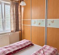 Schlafzimmer in einer 3-Zimmer-Wohnung mit Einbauschrank und Bett mit roter Bettwäsche.