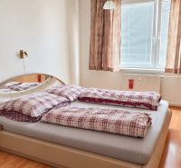 Schlafzimmer in einer 3-Zimmer-Wohnung mit Bett, Schrank unter dem Spiegel und Boden mit Holzdekor.