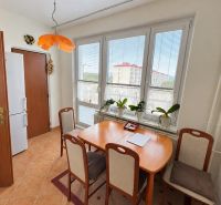 Esszimmer in einer 3-Zimmer-Wohnung mit Fenster, Pflanzen und quadratischem Tisch mit Stühlen.