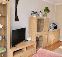 Wohnzimmer mit Holzmöbeln, dekorativen Blumen und einem Boden mit Holzdekor.