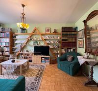 Wohnzimmer in einer 3-Zimmer-Wohnung mit Holzboden und einer umfangreichen Bibliothek.