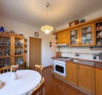 Küche in einer 3-Zimmer-Wohnung mit Holzelementen, Tellern und einer Vase mit Blumen.