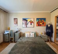 Schlafzimmer in einer 3-Zimmer-Wohnung mit Holzboden und Kunstgemälden an der Wand.