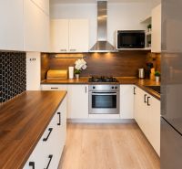 Küche in einer 2-Zimmer-Wohnung mit Holzdekor und schwarzen sechseckigen Fliesen.