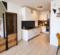 Küche in einer 2-Zimmer-Wohnung mit geometrischen Mustern und einem Boden in Holzoptik.