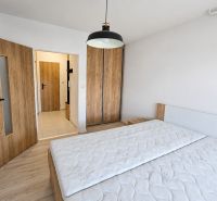 Schlafzimmer in einer 2-Zimmer-Wohnung mit Bett, Schrank und Boden in Holzoptik.