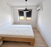 Schlafzimmer mit Bett, Klimaanlage und Holzboden in einer 2-Zimmer-Wohnung.