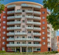 Ein Hochhaus mit interessanten Balkonen an der Bosákova-Straße, in der Nähe von Garagen in der Stadt.