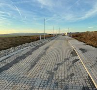 Straße in Vinohrady in Senica mit befestigter Oberfläche, umliegende Landschaft und Beleuchtungsmasten.