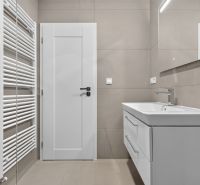 Badezimmer in einer 3-Zimmer-Wohnung mit Duschkabine, hellen Fliesen und weißen Möbeln.