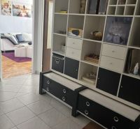 Der Flur in einer 2-Zimmer-Wohnung mit Fliesenboden und eingebautem Regal.