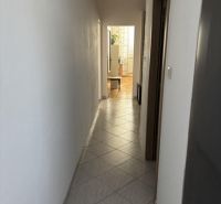 Ein enger Flur mit gefliestem Boden führt zu einem hellen Raum in einer Zweizimmerwohnung.
