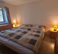 Ein Schlafzimmer in einem Einfamilienhaus mit einem Doppelbett, Holzkonsolen und Lampen.