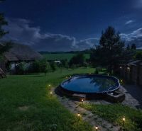 Nachtgarten eines Einfamilienhauses in Dobrá Voda mit beleuchtetem Pool.