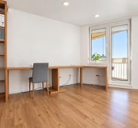 Ein Zimmer in einer 3-Zimmer-Wohnung mit Regalen, einem Tisch und einem Boden in Holzoptik.