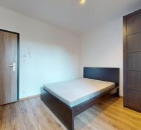 Einzimmerwohnung mit Bett und Schrank, Boden mit Holzdekor, weiße Wände.