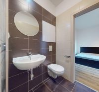Badezimmer mit Toilette, Duschkabine, Waschbecken, Blick auf den Raum, Einzimmerwohnung.