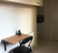 Arbeitsbereich in einer 2-Zimmer-Wohnung mit ausklappbarem Tisch und Regal.